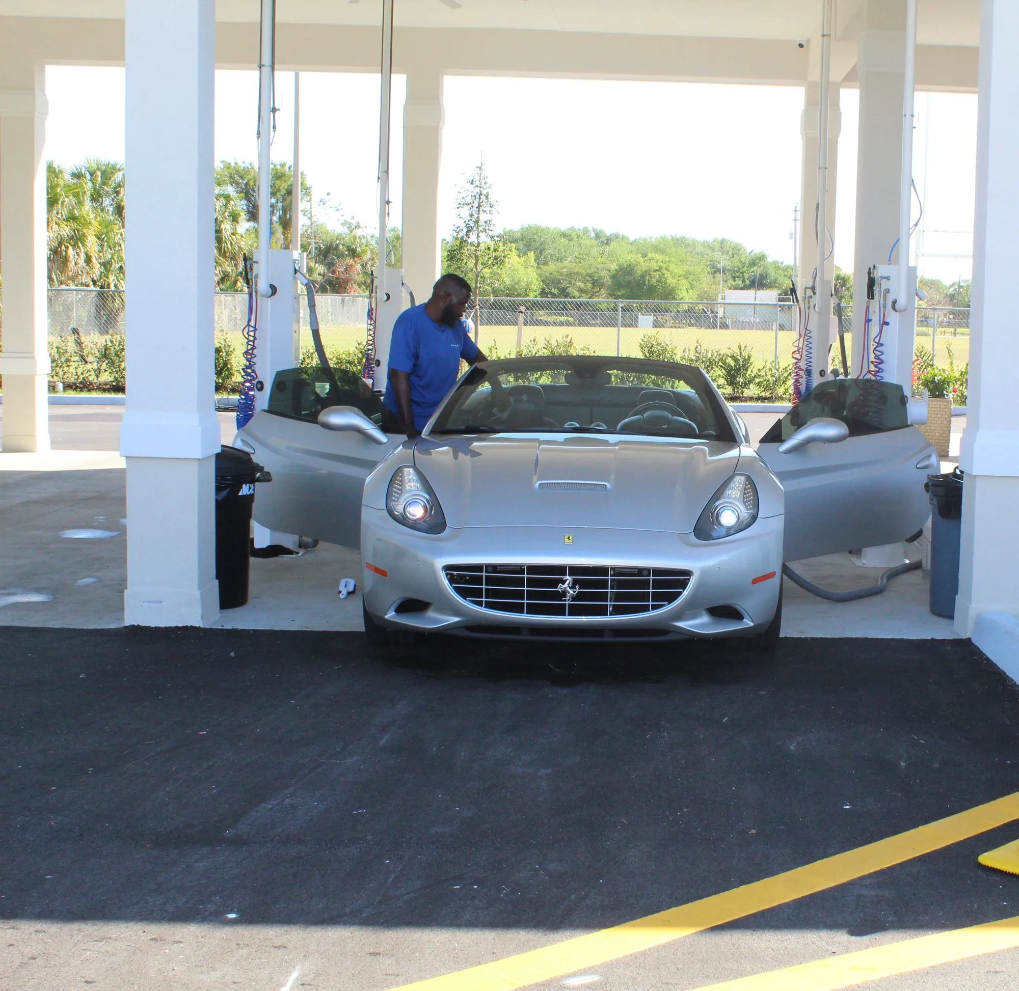 A silver Ferrari California drying in a covered wash bay