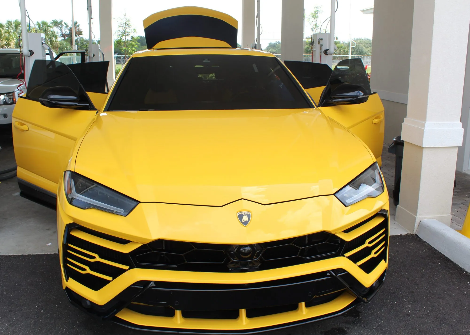 A yellow Lamborghini Urus with its doors open after detailing